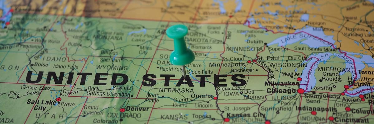 A green push pin in a wall map of the United States, with the Rocky Mountains, the Great Plains and the Great Lakes around it.