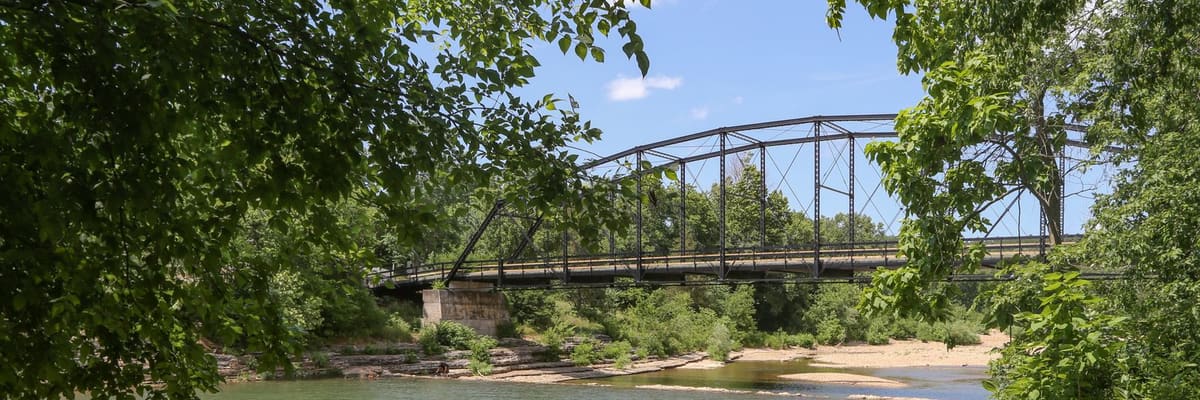 War Eagle Bridge crossing a calm river among green trees in Arkansas
