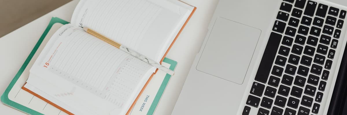 An open planner and a laptop on a white desk, seen from above, beside the clinical psychologist salary figures