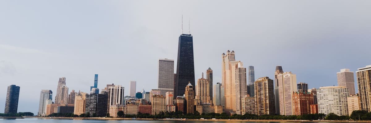 The Chicago, Illinois skyline reflected in calm lakefront water under a clear sky