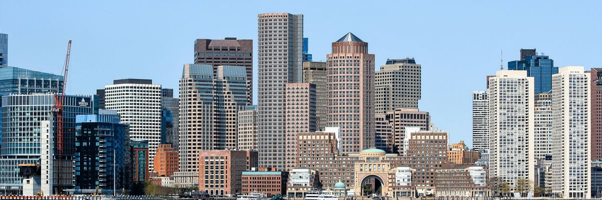 The Boston, Massachusetts skyline and harbor waterfront under a clear blue sky