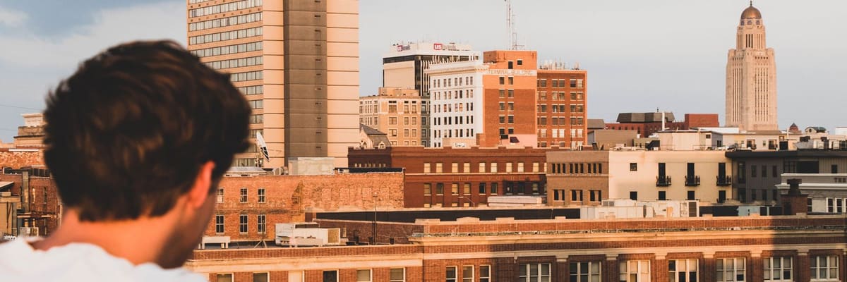 The Lincoln, Nebraska skyline at sunset with the State Capitol tower, and a young man looking out over the city