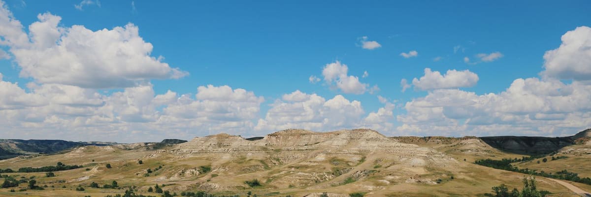 Rolling landscape of Theodore Roosevelt National Park, North Dakota, under a bright summer sky
