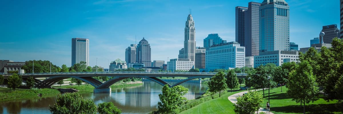 The Columbus, Ohio skyline with modern skyscrapers and a green park along the river