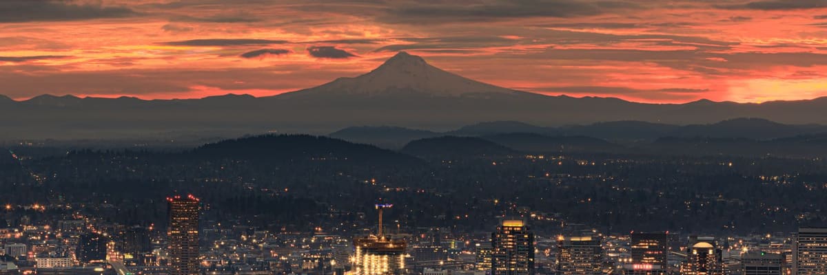 Portland, Oregon at sunset with illuminated buildings and Mount Hood in the background