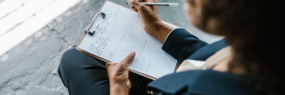 Close-up of a psychologist writing notes on a clipboard during a counseling session, the work behind the psychologist salary figures