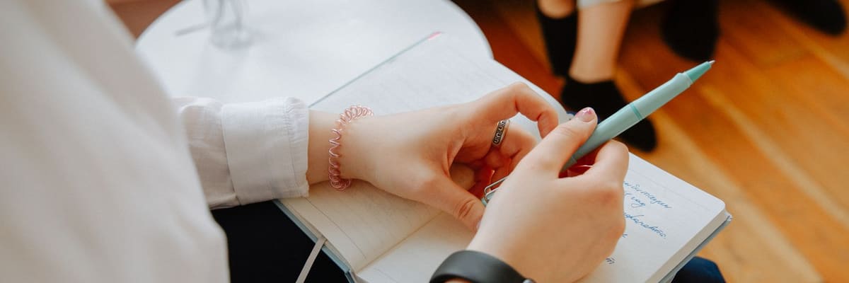 Hands holding a pen over an open notebook during a counseling session