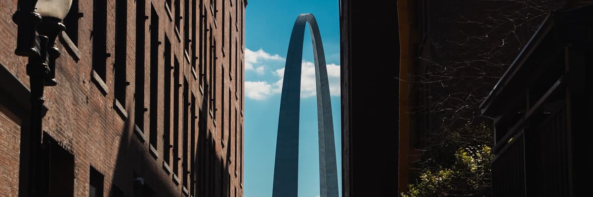 The Gateway Arch rising into blue sky between old brick warehouse buildings in St. Louis, Missouri. The photograph opens the ranking of PsyD programs in Missouri.
