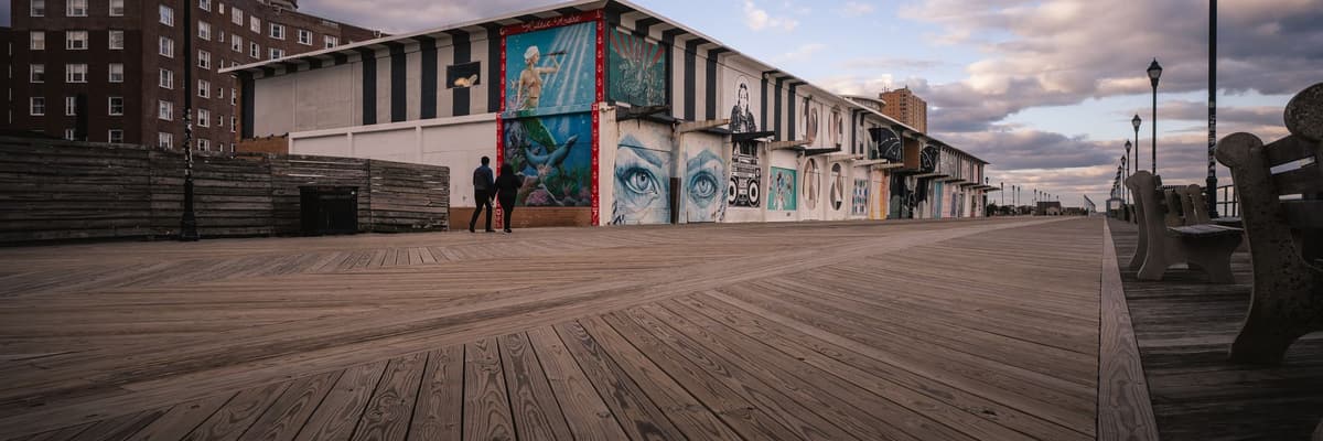 The boardwalk at Asbury Park, New Jersey, with murals on a beachfront building and benches along the planks. The photograph opens the ranking of PsyD programs in New Jersey.
